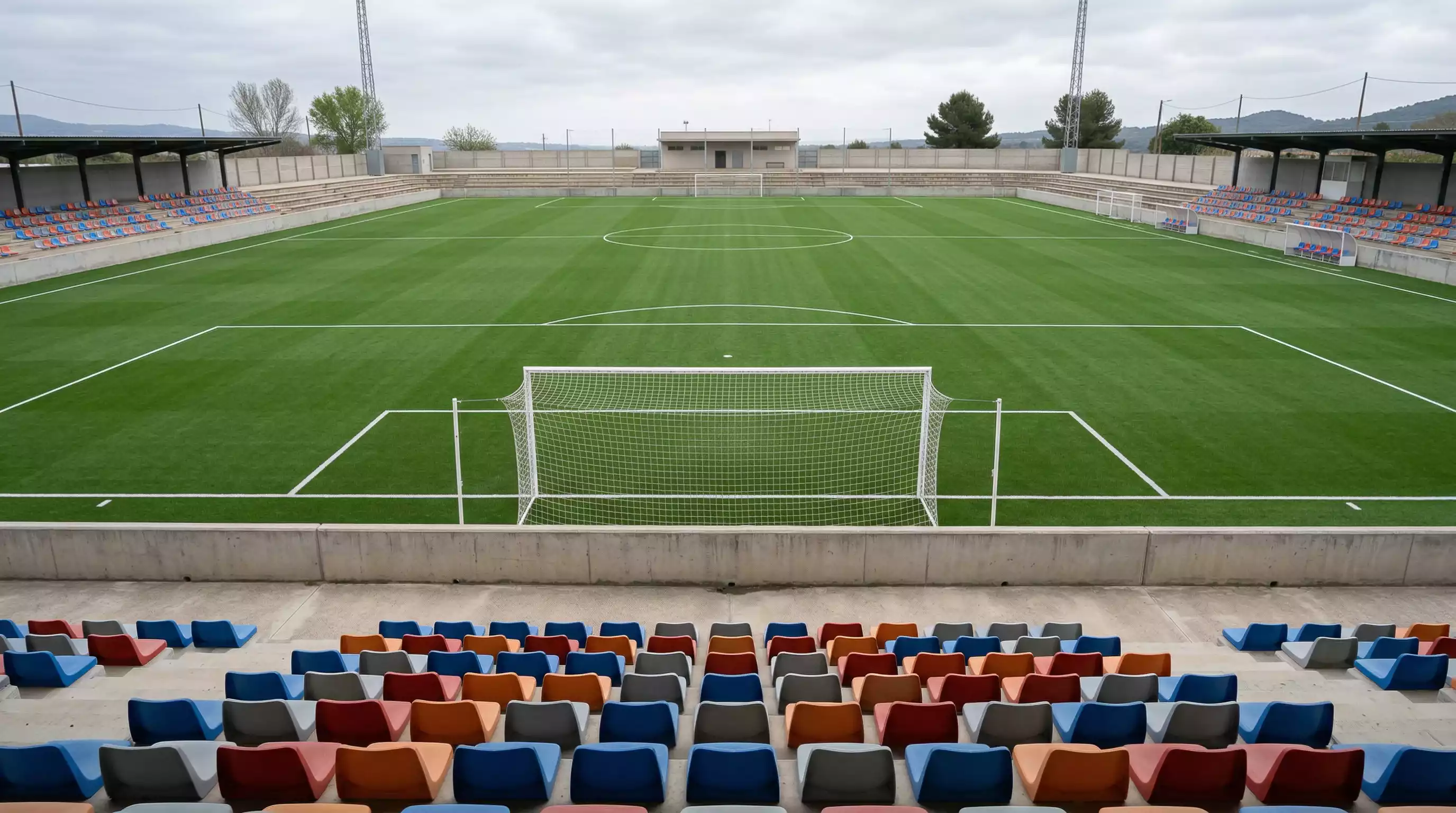 Grada de un estadio italiano pequeno con asientos vacios y el campo de futbol verde visto desde una esquina